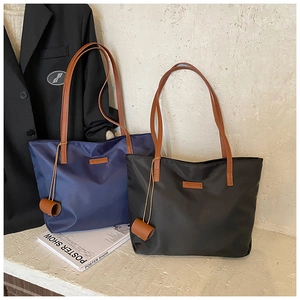 Dettagli di borse tote blu e nere con manici in pelle marrone per abbigliamento da lavoro
