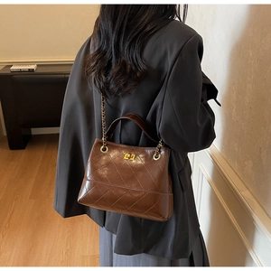 Detailansicht der dunkelbraun gesteppten Lederhandtasche mit goldenem Drehverschluss