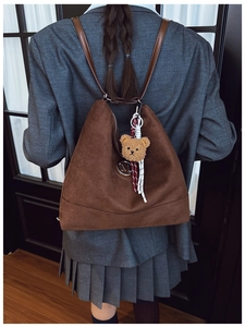 Vue détaillée du sac à dos en daim marron avec logo M et charm ours en peluche sur le dos