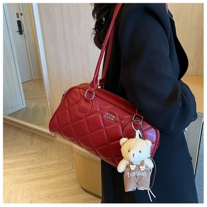 Detail of dark red quilted crossbody bag with leather straps and cute plush bear charm