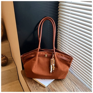 Detailansicht der caramelfarbenen Wildleder-Shopper-Tasche mit ethnischem Perlenanhänger
