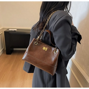 Detailansicht der braunen gesteppten Tasche mit goldener Kette und Lederstruktur