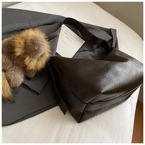 Détail du sac à bandoulière en simili cuir marron foncé poli avec texture froissée