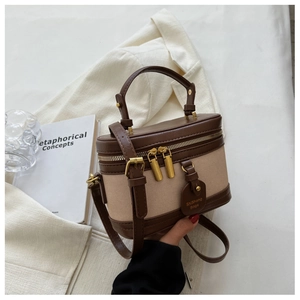 Détail d'un sac boîte vintage en cuir marron et toile beige avec surpiqûres élégantes