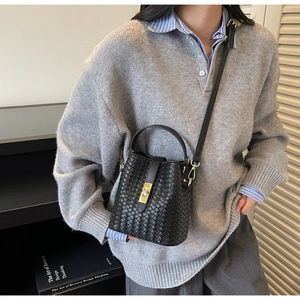Detail of black woven leather bucket bag featuring gold twist lock and fine braided texture