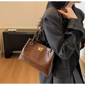 Detail der braunen gesteppten Ledertasche mit goldener Kette und Drehverschluss