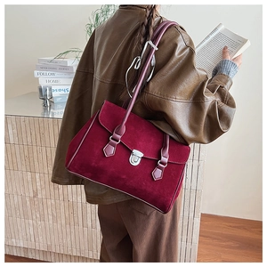 Detail of dark red matte suede handbag featuring a vintage metal clasp and long thin handles