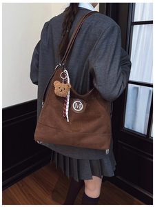 Détail du sac fourre-tout marron vintage avec logo M, breloque ours et bandoulière