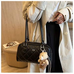 Detail of quilted black leather shoulder bag with a cute brown teddy bear charm