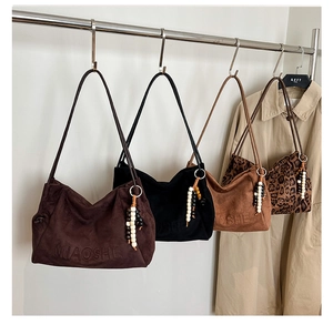 Detail of suede shoulder bags with MIAOSHE logo and decorative beaded tassel charms