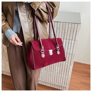 Detail of burgundy frosted leather shoulder bag with silver metallic clasp and long strap
