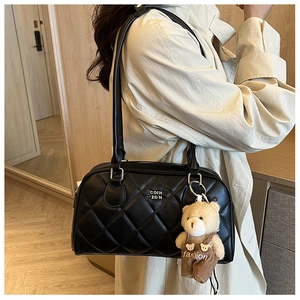 Detailed view of black quilted leather shoulder bag with cute teddy bear plush charm
