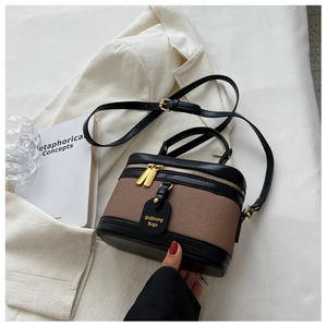 Détail du sac seau vintage en toile et cuir avec ferrures dorées et étiquette de marque