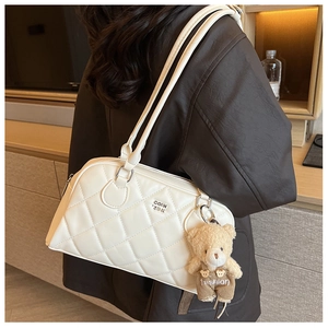 Close-up of white quilted handbag with zipper closure and cute teddy bear charm