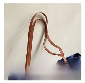 Dettaglio della borsa tote in nylon blu con manici in finta pelle marrone e patch