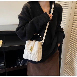 Close-up of white woven leather bucket bag featuring a gold twist lock and handle