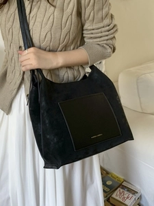 Retro black faux suede tote bag with leather pocket shown on model in cozy home setting