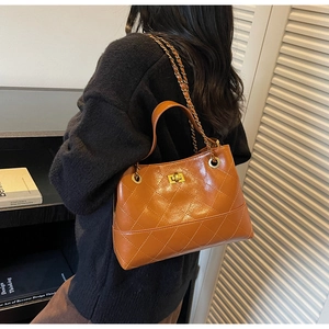 Detail der karamellbraunen Stepptasche mit goldenem Drehverschluss und Kettenriemen
