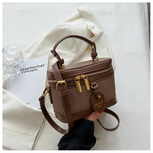 Détail du sac seau en toile marron avec fermetures dorées et bandoulière en cuir