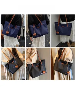 Dettaglio della grande borsa tote in nylon con manici in pelle e piccolo ciondolo abbinato