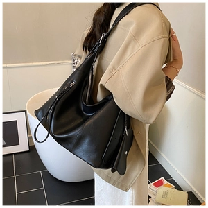 Detail of minimalist black leather tote bag with silver zippers and adjustable strap