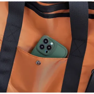 Detail of orange canvas bag featuring a snap pocket holding a smartphone for scale