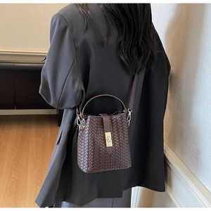 Model showcasing a dark brown woven leather bucket bag with golden twist-lock closure