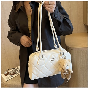 Detail of white quilted crossbody bag with silver logo and cute brown bear pendant