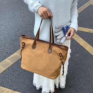 Detail of caramel suede tote bag with brown leather handles and side drawstring accents