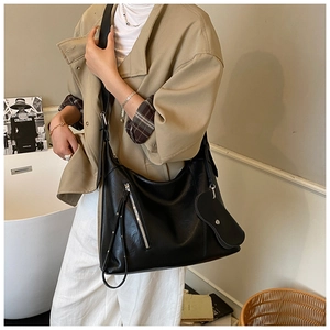 Close-up of black pebble leather tote bag with silver zipper and heart charm detail