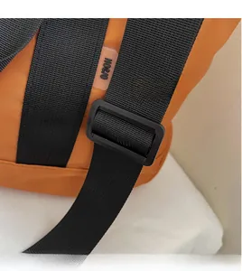 Detail view of the orange canvas bag showing adjustable black shoulder strap and buckle
