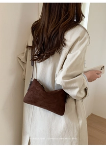 Détail du sac à bandoulière en daim marron foncé au design rétro minimaliste sur modèle