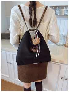 Détail d'un sac cabas noir mat avec logo M en cuir marron et breloque d'ours en peluche
