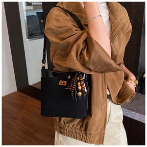 Detailweergave van zwarte vintage crossbodytas met gouden gesp en kwastjesbedel
