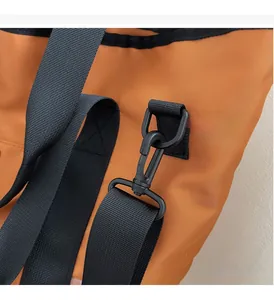 Detail of durable black metal swivel hook and woven strap on a bright orange canvas bag
