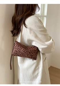Détail d'un sac baguette léopard porté avec un trench beige pour un style rétro chic