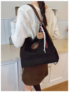 Détail du sac hobo noir avec logo M, bandoulière en cuir brun et pendentif d'ours