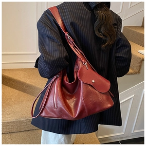 Deep burgundy leather hobo bag with silver zippers shown on a model's shoulder