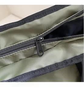 Detailed close-up of the smooth black zipper and durable nylon fabric on the green bag