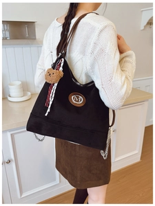 Détail du sac cabas noir mat avec chaîne argentée, breloque ours et logo M
