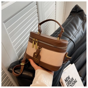 Détail du sac boîte vintage avec bordures en cuir marron et texture toile beige