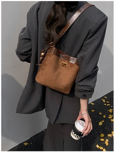 Detailed view of vintage brown suede bucket bag with leather trim and wooden bead charm