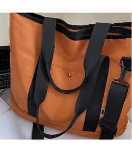 Detail of the durable handle and orange water-resistant nylon fabric on the large tote bag