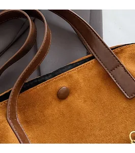 Detail of the magnetic buckle closure and suede texture on a large brown tote bag