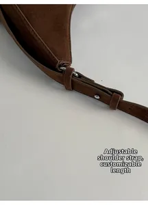 Détail macro de la bandoulière réglable en daim avec rivets métalliques sur sac bandoulière