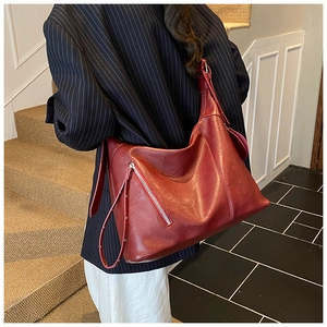Detail view of the large capacity dark red shoulder bag with silver metal zippers