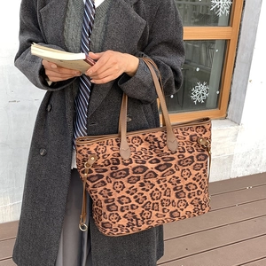 Detail of leopard print tote bag featuring leather handles and side drawstring hardware