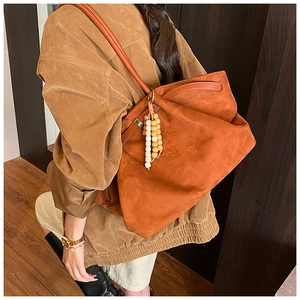 Detail der orangefarbenen Wildleder-Shopper mit Holzperlenquaste und Schultergurt