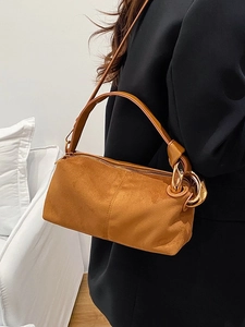 Vintage brown suede cylinder shoulder bag with gold metal rings on a fashion model