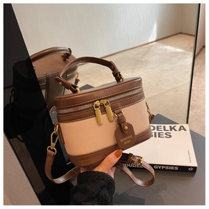 Détail du sac boîte cylindrique rétro en cuir marron et toile beige contrastée